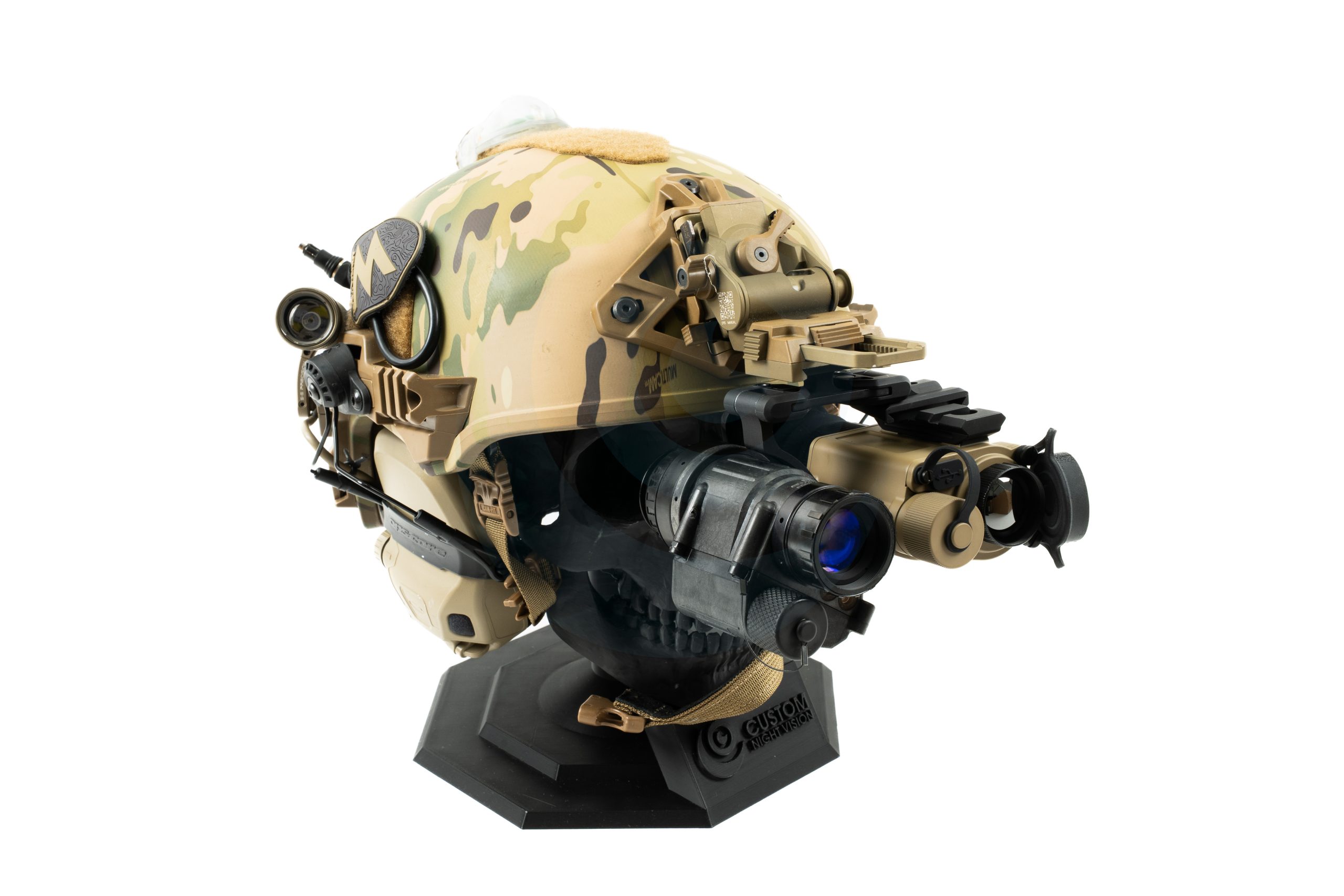 Camouflage tactical helmet with mounted night vision goggles on display stand.