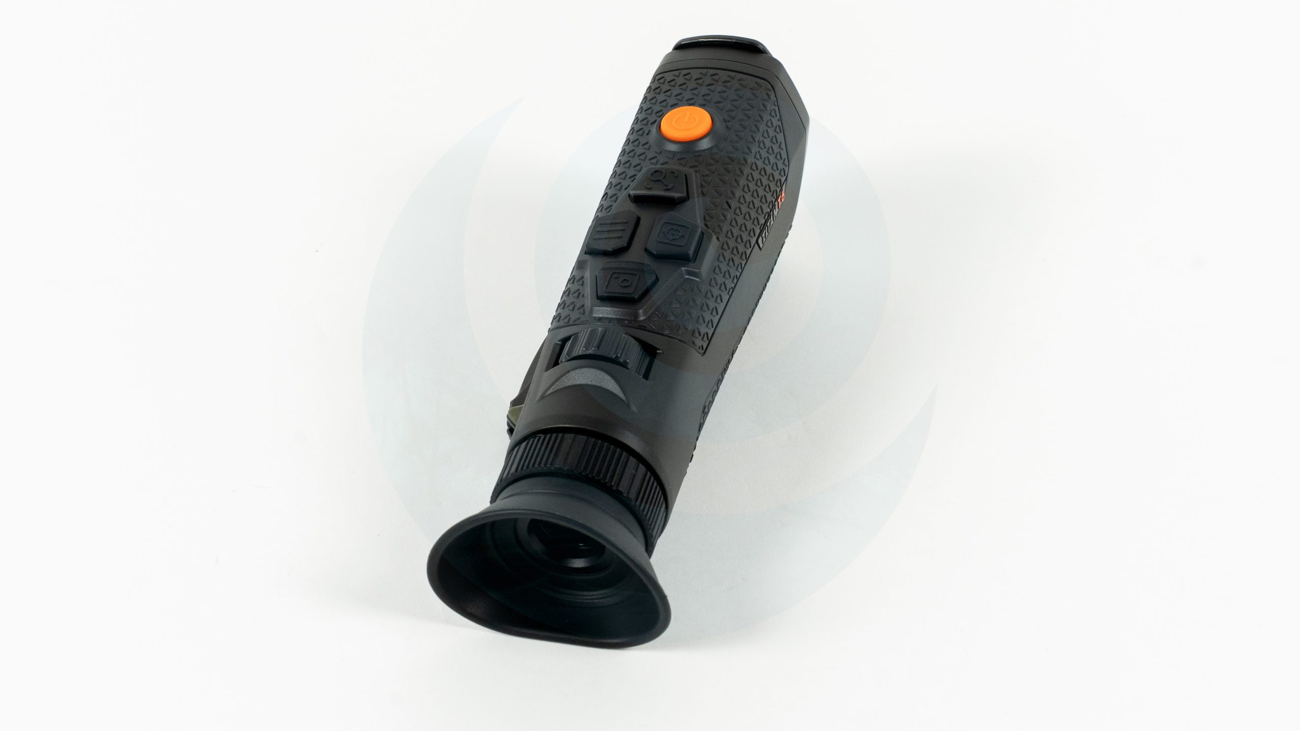Black handheld night vision monocular with orange power button on white background