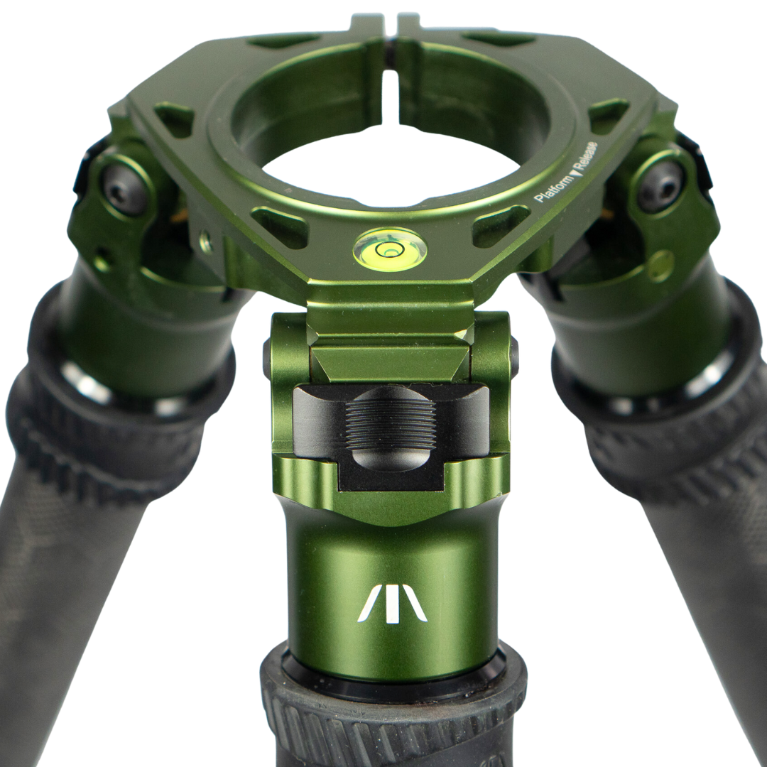 Close-up of a green metal tripod mount with bubble level and textured grips.