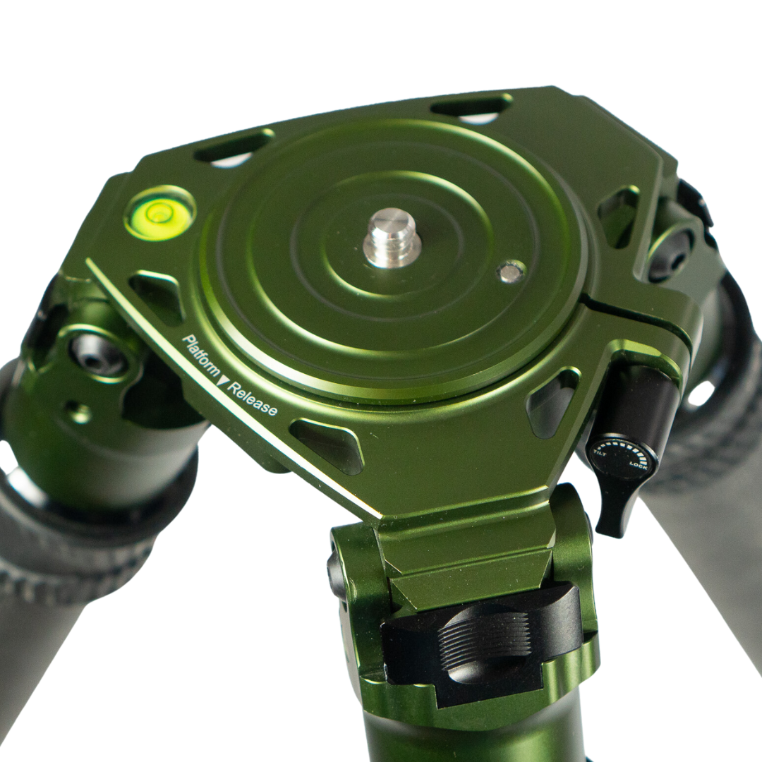 Close-up of a green tripod head with platform release mechanism.