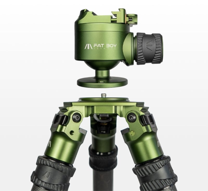 Close-up of a green Fat Boy tripod with adjustable head on a white background.