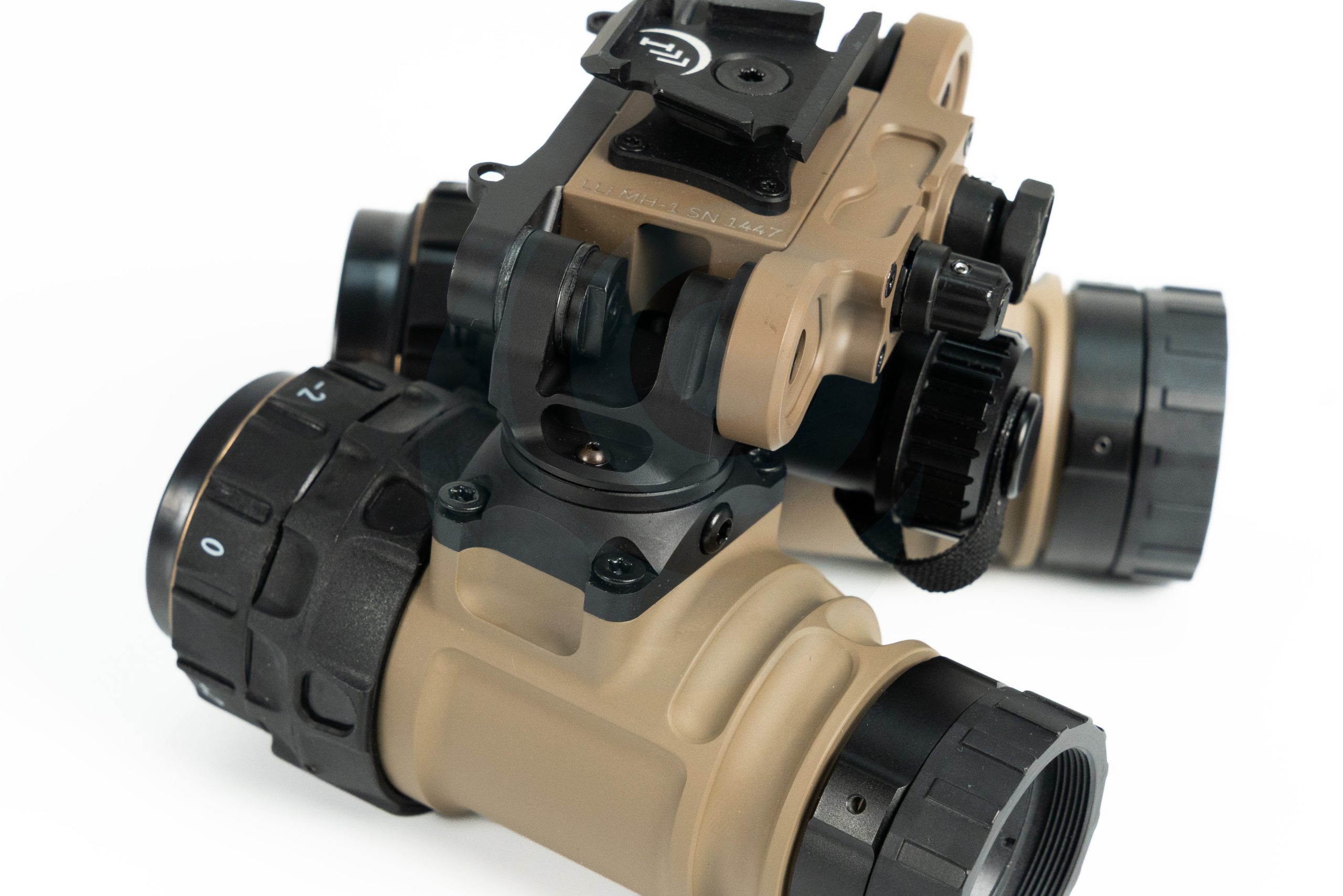 Close-up of tan night vision goggles with black adjustment knobs on a white background.